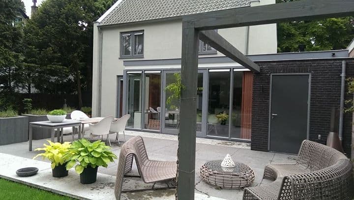 Strakke tuin met een terras en loungestoelen bij een moderne woning